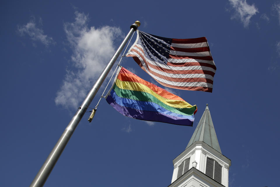 FILE - A gay pride rainbow flag flies with the U.S. flag in front of the Asbury United Methodist Church in Prairie Village, Kan., on Friday, April 19, 2019. The United Methodist Church moved toward becoming more progressive and LGBTQ-affirming during U.S. regional meetings in November 2022, that included the election of its second openly gay bishop. Conservatives say the developments will only accelerate their exit from one of the nation’s largest Protestant denominations. (AP Photo/Charlie Riedel, File)