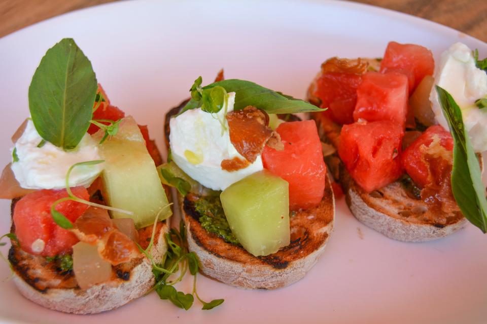 The burrata and melon tartine appetizer at Farmhouse Kitchen restaurants in Delray Beach and Boca Raton features arugula pesto, pine nut agrodolce and prosciutto bits.