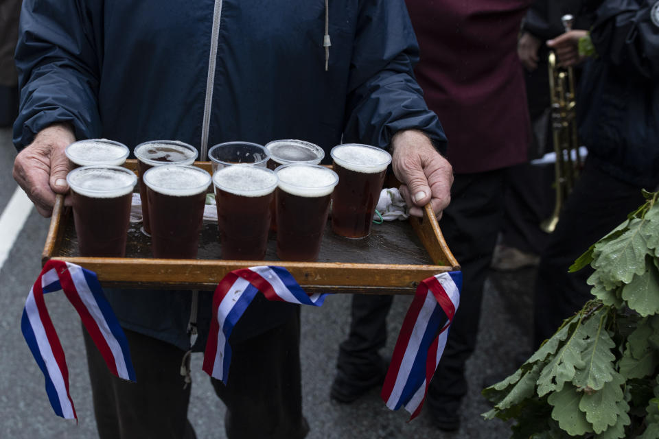 CASTLETON, ENGLAND - MAY 29: Drinks are served to the band at one the the towns pubs during 'Castleton Garland Day' on May 29, 2019 in Castleton, England. The procession stops at every pub in the village before the Garland is hoisted onto the top of the church. The first records of Garland day date back to the 1700's and though it's true origins are not fully understood it is believed to be an ancient fertility rite with Celtic connections. The celebration also incorporates more recent elements of 'Oak Apple Day' which falls on May 29th, and celebrates the restoration of the monarchy in 1660. The garland is a framework of cut flowers which is prepared on the day by villagers before being placed on the head of the 'King', and paraded around the town on horseback with his 'Consort', also on horseback, dressed in Stuart costume. (Photo by Dan Kitwood/Getty Images)