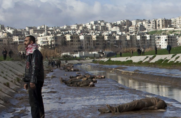 A Syrian man stands next to the bodies of executed men on the side of a canal in the northern city of Aleppo on January 29, 2013. The bodies of 78 young men, all executed with a single gunshot, were found Tuesday in a river in Aleppo city, adding to the grim list of massacres committed during Syria's 22-month conflict