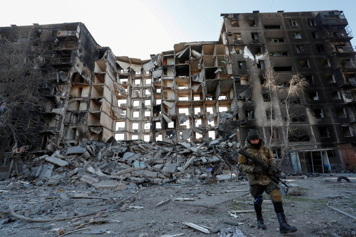 A soldier walks near an apartment building that has been destroyed.