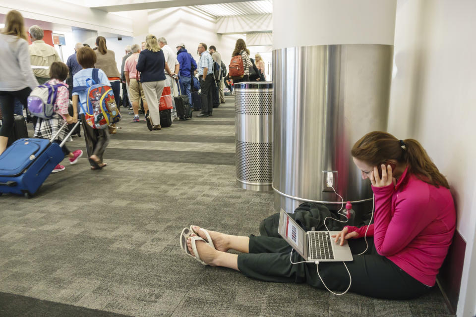 A woman sat on the floor in Los Angeles, LAX, international airport charging her laptop. (Photo by: Jeffrey Greenberg/Universal Images Group via Getty Images)