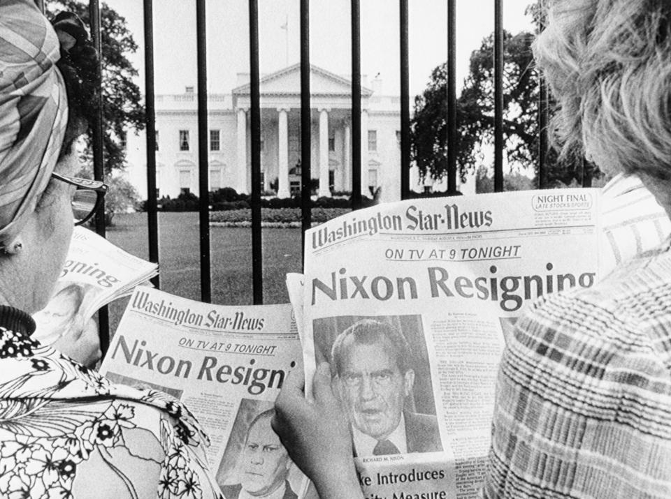 8/8/1974-Washington, DC- Newspaper headlines being read by tourists in front of the White House tell of history in the making. (Bettmann Archive/Getty Images)