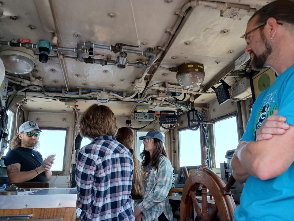 Brandon Fiew, left, talks to high school students about the many paths they could take to contribute to science, near the end of a day learning how to do basic research aboard the UW-Milwaukee research vessel, the Neeskay. Max Morgan, right, captain of the boat, listens in.