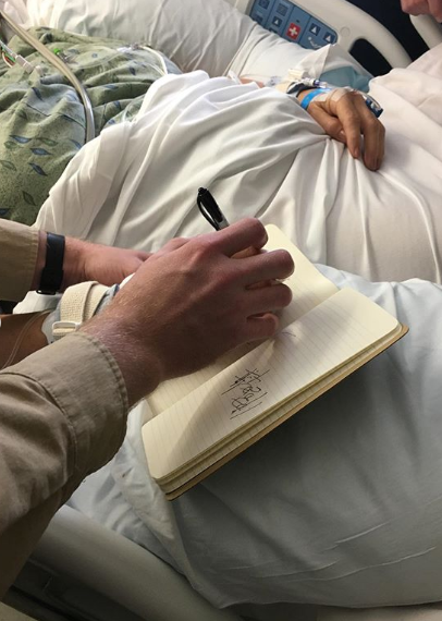 A photo of Tina Hines in hospital writing in a notepad.