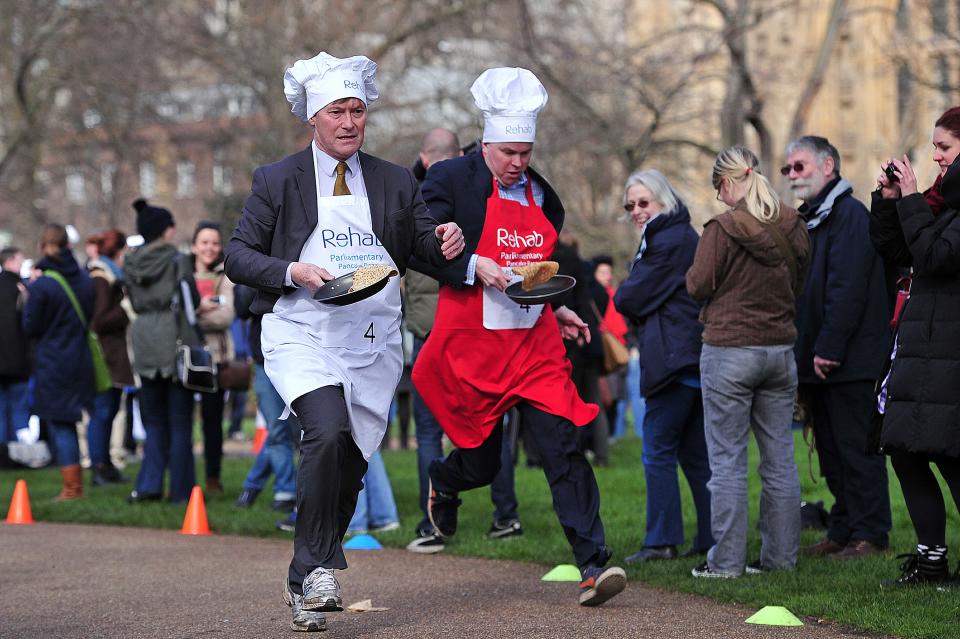 British parliamentarian David Amess MP (L) and BBC journalist Robbie Gibb, take part in the annual parliamentary pancake race on Shrove Tuesday in central London on March 4, 2014. AFP PHOTO / CARL COURT        (Photo credit should read CARL COURT/AFP via Getty Images)