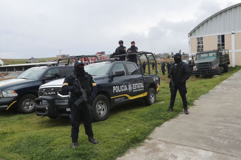 Police officers stand in formation at an area following villagers' bloody takedown of extortionists in Texcapilla