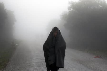 An Afghan migrant walks through rain and fog on his way to the nearest registration camp on the Greek island of Lesbos October 22, 2015. REUTERS/Yannis Behrakis