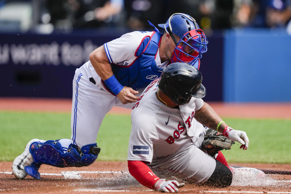 Toronto Blue Jays catcher Tyler Heineman (55) tags Boston Red Sox's Rafael Devers (11) out at home plate during the second inning of a baseball game in Toronto, Sunday, Sept. 17, 2023. (Andrew Lahodynskyj/The Canadian Press via AP)