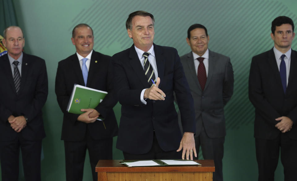 Brazil's President Jair Bolsonaro gives a thumbs up after signing a decree that loosens restrictions on owning a firearm at Planalto presidential palace in Brasilia, Brazil, Tuesday, Jan. 15, 2019. Standing behind him are, from left, Defense Minister Fernando Azevedo e Silva, Chief of Staff Onix Lorenzoni, Vice President Hamilton Mourao and Justice Minister Sergio Moro. (AP Photo/Eraldo Peres)