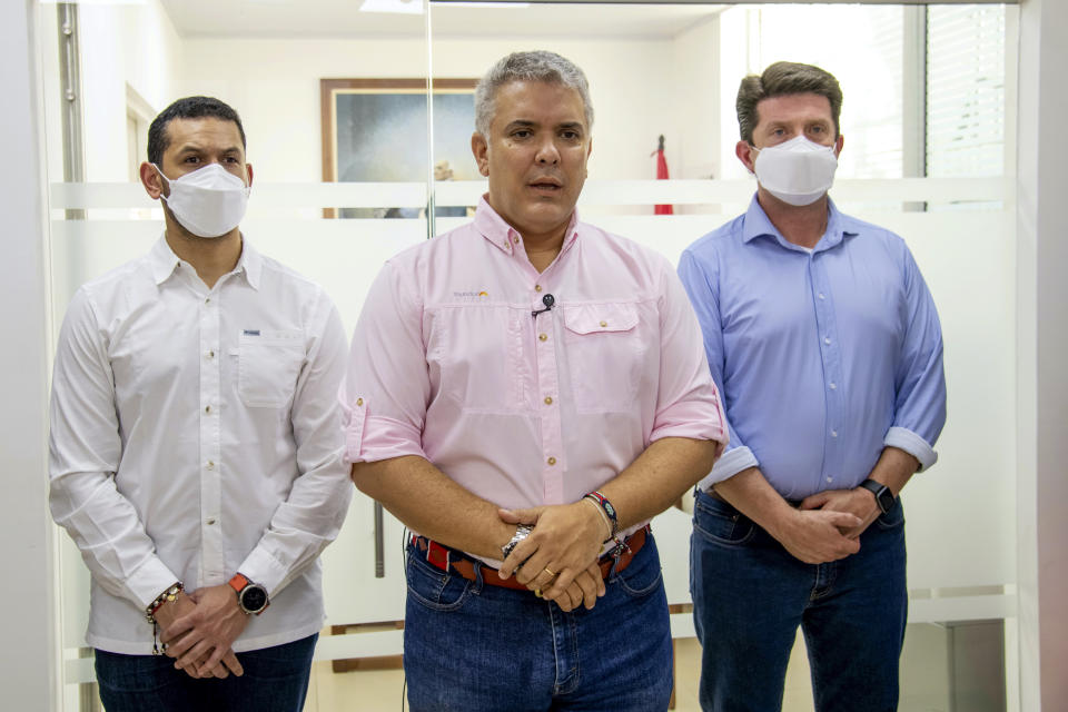 In this photo released by Colombia's Presidency, President Ivan Duque speaks, flanked by Interior Minster Daniel Palacios, left, and Defense Minister Diego Molano, in Cucuta, Colombia, Friday, June 25, 2021. Duque said that the helicopter they were traveling on was attacked at the Catatumbo region, on the northeastern border with Venezuela. (Cesar Carrion/Presidency of Colombia via AP)