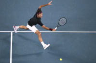 Switzerland's Roger Federer makes a backhand return to Australia's John Millman during their third round singles match at the Australian Open tennis championship in Melbourne, Australia, Friday, Jan. 24, 2020. (AP Photo/Dita Alangkara)