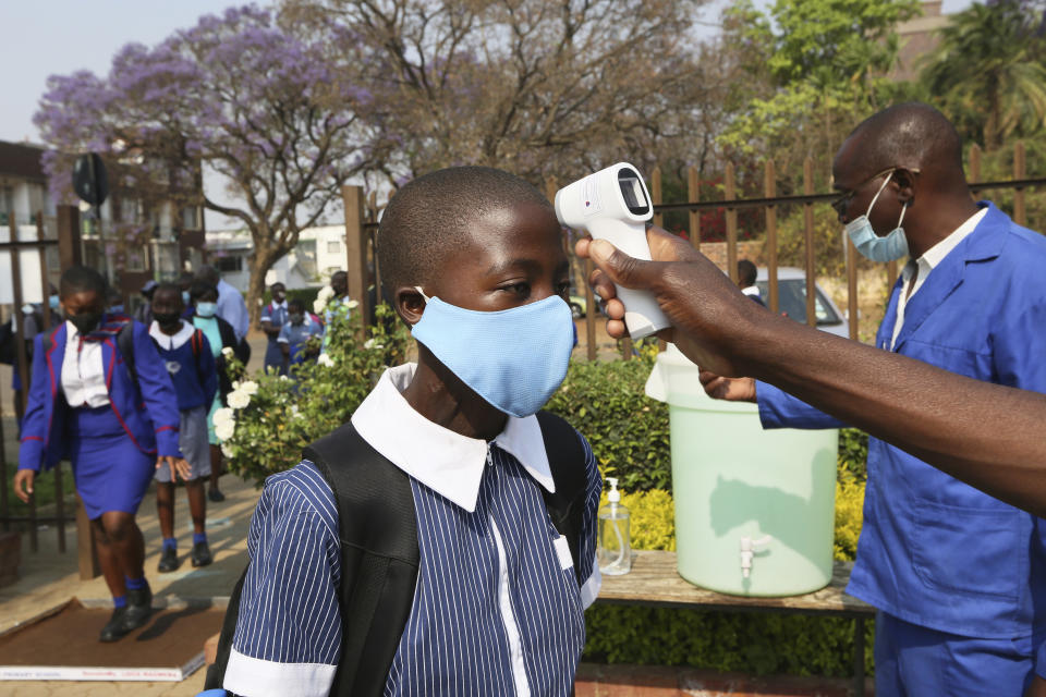 A child gets her temperature checked before entering school in Harare, Zimbabwe, Monday, Sept, 28, 2020. Zimbabwe schools have reopened in phases, but with smaller number of pupils,more teachers and other related measures to enable children to resume their education without the risk of a spike in COVID-19 infections. (AP Photo/Tsvangirayi Mukwazhi)