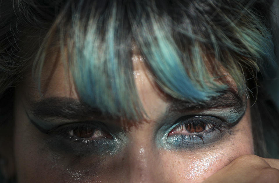 An anti-government protester wipes her eyes, affected by tear gas launched by Chilean police during protest in Santiago, Chile, Wednesday, Nov. 6, 2019. Chile's president Sebastian Pinera announced he is sending a bill to Congress that would raise the minimum salary, one of a series of measures to try to contain nearly three weeks of anti-government protests. (AP Photo/Esteban Felix)