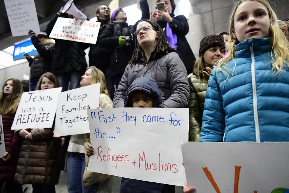 Stephanie Hartley-Bah and her son Jah'kier Hartley, 7, both of Bear, Del., listen during a protest of President Donald Trump's travel ban on refugees and citizens of seven Muslim-majority nations, Sunday, Jan. 29, 2017, at Philadelphia International Airport in Philadelphia. (AP Photo/Corey Perrine)