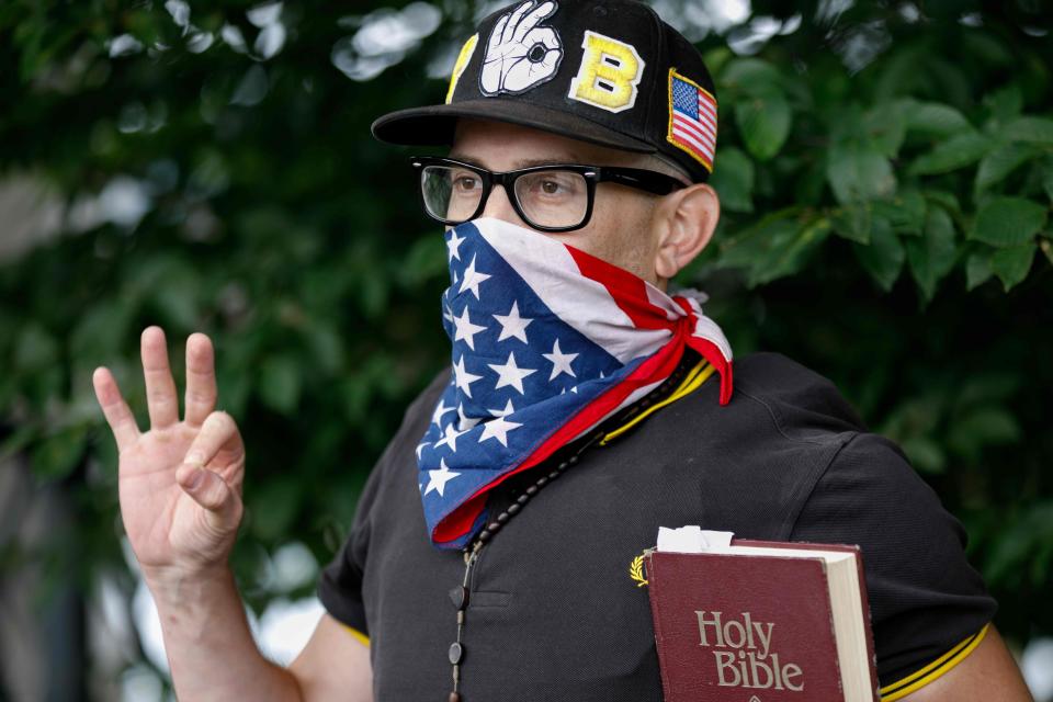 A member of the "Proud Boys" far-right group holds a bible and displays the OK hand gesture believed to have white supremacist connotations during "The End Domestic Terrorism" rally at Tom McCall Waterfront Park on August 17, 2019 in Portland, Oregon.