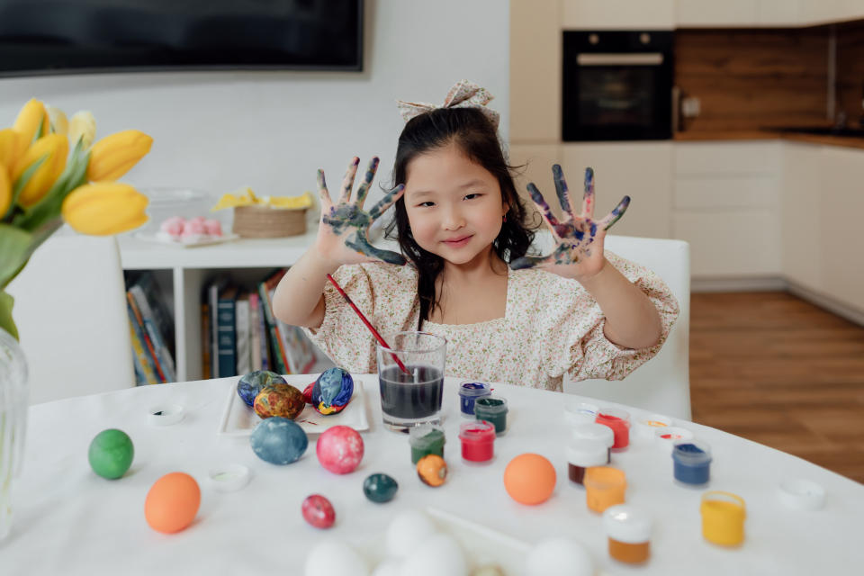 Canadians should avoid harsh chemicals or scrubs to prevent irritating skin when cleaning off dye. (Getty) A little Asian girl sits at a table in the kitchen at home in the ears of a hare and paints Easter eggs, shows her hands stained in paint