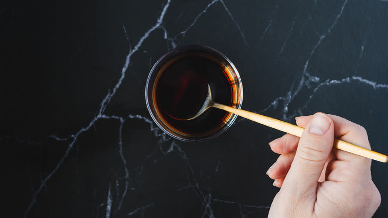 Hand stirring drink with golden spoon