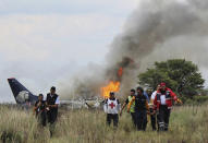 <p>In this photo released by Red Cross Durango communications office, Red Cross workers and rescue workers carry an injured person on a stretcher, right, as airline workers, left, walk away from the site where an Aeromexico airliner crashed in a field near the airport in Durango, Mexico, Tuesday, July 31, 2018. The jetliner crashed while taking off during a severe storm, smacking down in a field nearly intact then catching fire, and officials said it appeared everyone on board escaped the flames. (Photo: Red Cross Durango via AP) </p>