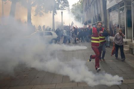 A man runs away from tear gas during clashes with French riot police at a march in Nantes, western France, to demonstrate against the new French labour law, September 15, 2016. REUTERS/Stephane Mahe