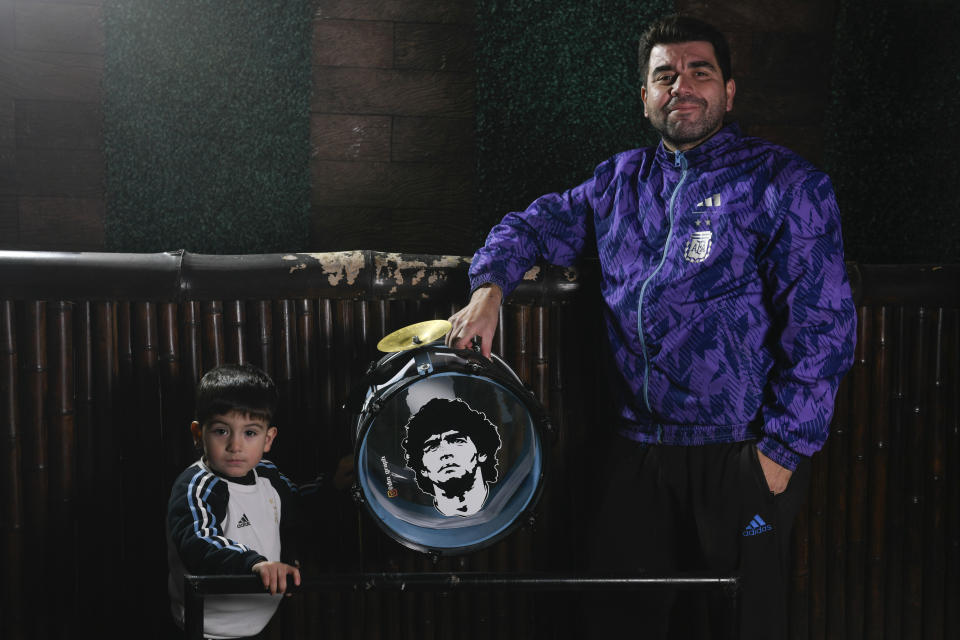 El aficionado argentino Matías Celestino y su hijo Benito Lionel posan para una foto con un bombo con la imagen de Diego Maradona en su residencia en Buenos Aires, Argentina, el lunes 3 de junio de 2024. La familia de Celestino viajará a Estados Unidos para seguir la Copa América. (AP Foto/Gustavo Garello)