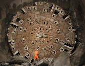 A miner stands in front of the drill machine 'Sissi' after it broke through the rock at the final section Faido-Sedrun, at the construction site of the NEAT Gotthard Base Tunnel October 15, 2010. With a length of 57 km