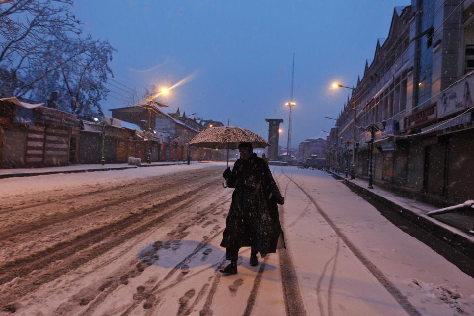 A man walks under an umbrella during snowfall on a cold winter morning in Srinagar December 31, 2013. Temperatures in Srinagar, which received the season's second snowfall on Tuesday, dipped to -1.4 degrees Celsius (29.5 degrees Fahrenheit), according to India's metrological department website. REUTERS/Danish Ismail (INDIAN-ADMINISTERED KASHMIR - Tags: ENVIRONMENT)