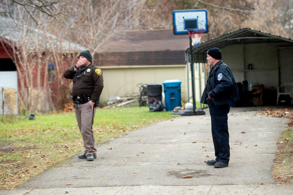 An Oakland County Sheriff's deputy, left, and an Oxford police officer search the grounds outside of the Crumbley residence while seeking James and Jennifer Crumbley