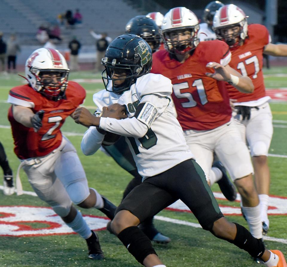 Logan Loveland and Tanner Collette (51) of Monroe chase Ann Arbor Huron quarterback Andrew Harding during a 40-0 Monroe loss Friday.