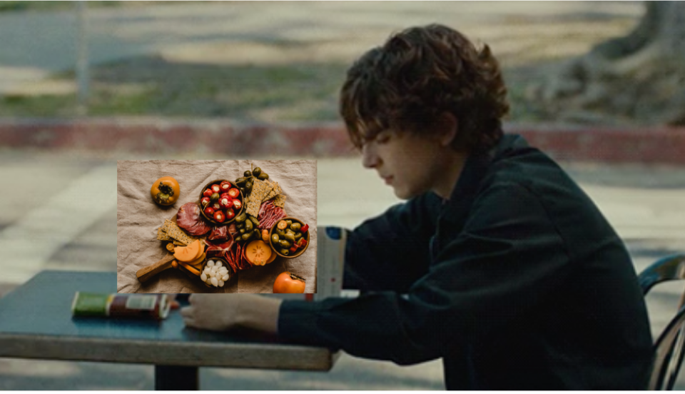 Timmy sitting at a table with a photo of a charcuterie board above his hands