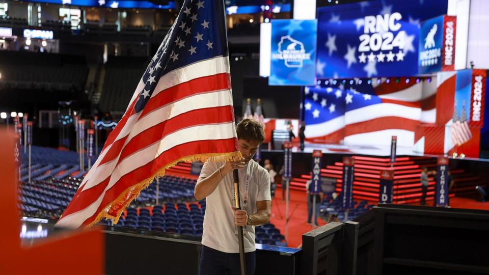 PHOTO: A worker places an American flag in the Fiserv Forum in preparation for the Republican National Convention, July 14, 2024, in Milwaukee, Wisconsin.  (Joe Raedle/Getty Images)