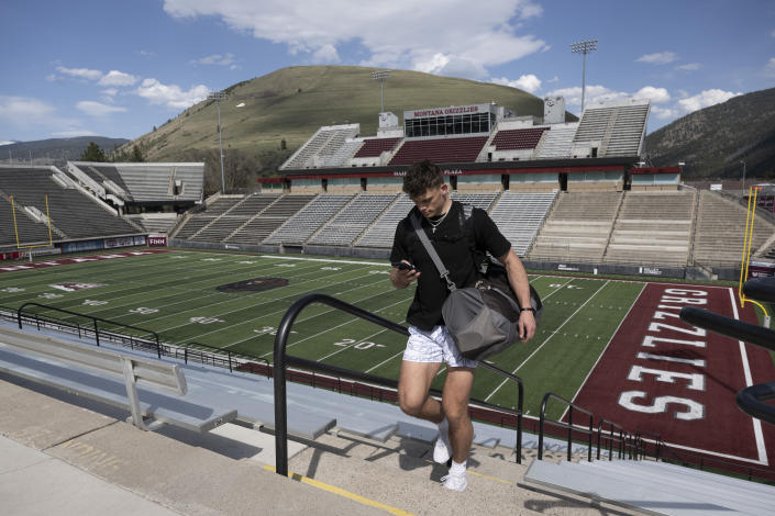 Adam Botkin, a football TikTok influencer, uses his phone after recording a video for a post at Washington-Grizzly Stadium in Missoula, Mont., on Monday, May 1, 2023. Botkin, a former walk-on place kicker and punter for the Montana Grizzlies, gained notoriety on the social media platform after videos of him performing kicking tricks went viral. (AP Photo/Tommy Martino)