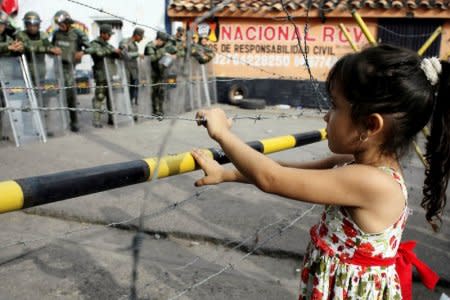 FILE PHOTO - A girl stands next to a barbed wire fence as she waits to try to cross the border to Colombia over the Francisco de Paula Santander international bridge in Urena, Venezuela December 18, 2016. REUTERS/Carlos Eduardo Ramirez