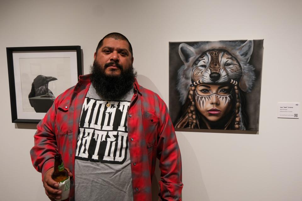 Juan Dash Jimenez stands by his painting "Wolf Princess" at the 20x20 Art Exhibition and Silent Auction at the Amarillo Museum of Art on the campus of Amarillo College.