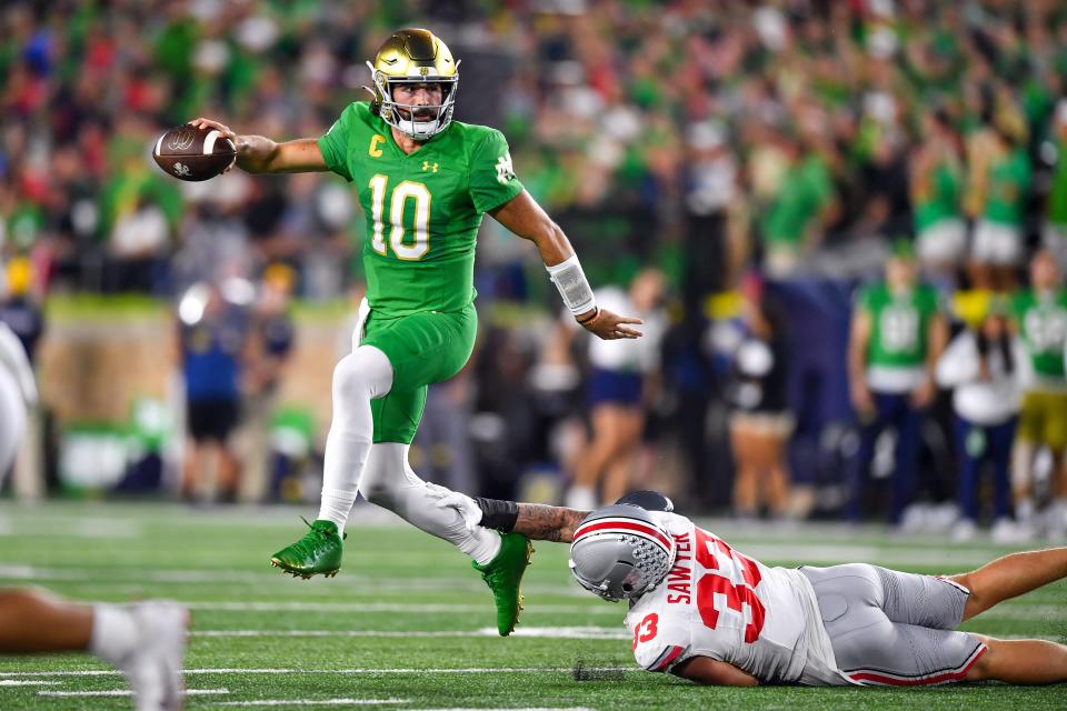 Notre Dame quarterback Sam Hartman (10) escapes pressure from Ohio State defensive end Jack Sawyer (33) in the first quarter.