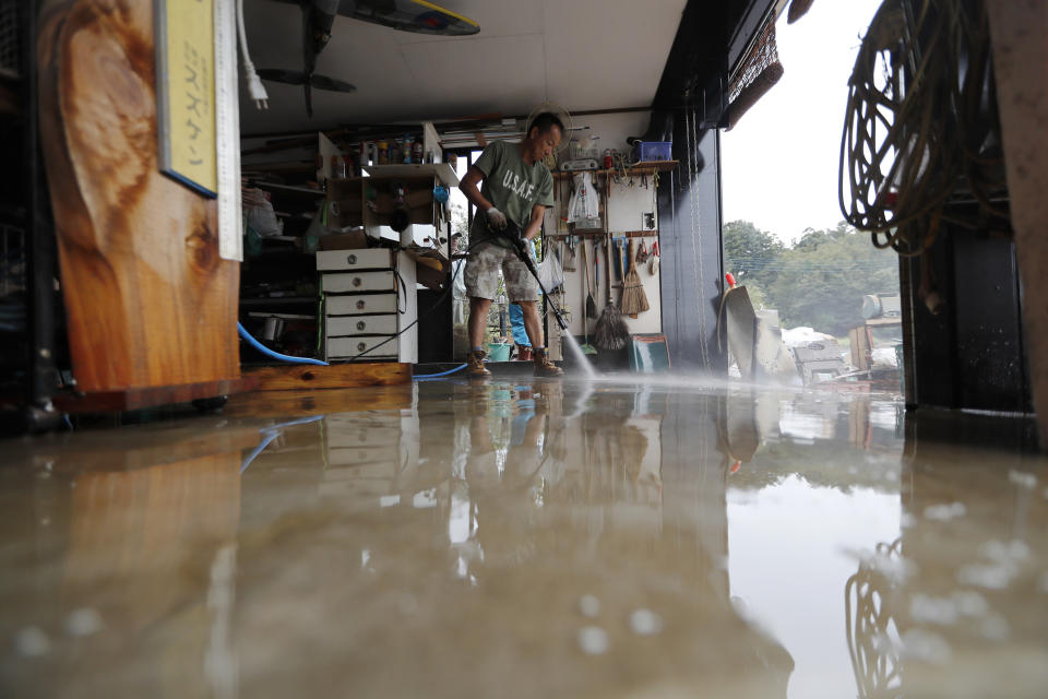 A volunteer helps clean up Monday, Oct. 14, 2019, in Kawagoe City, Japan. Typhoon Hagibis dropped record amounts of rain for a period in some spots, according to meteorological officials, causing more than 20 rivers to overflow. Some of the muddy waters in streets, fields and residential areas have subsided. But many places remained flooded, with homes and surrounding roads covered in mud and littered with broken wooden pieces and debris. (AP Photo/Eugene Hoshiko)