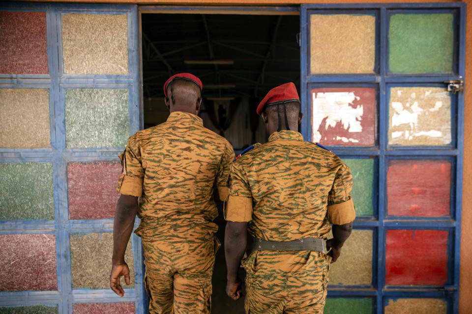 Two soldiers enter the Catholic church at the 10th RCAS army barracks in Kaya, Burkina Faso, Saturday, April 10, 2021. Once considered a beacon of peace and religious coexistence in the region, the West African nation has been embroiled in unprecedented violence linked to al-Qaida and the Islamic State since 2016, throwing an ill-equipped and undertrained army into disarray — and overwhelming the chaplains tasked with supporting them. (AP Photo/Sophie Garcia)