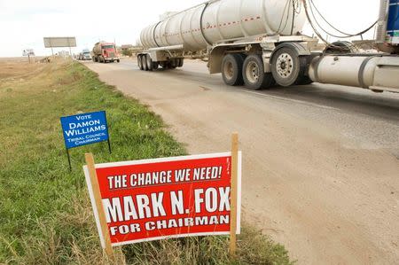 Oil field traffic passes a campaign sign for Three Affiliated Tribes council chairman candidates Mark Fox and Damon Williams in New Town on the Fort Berthold Reservation in North Dakota, November 1, 2014. REUTERS/Andrew Cullen