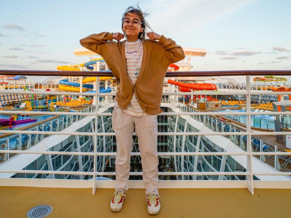 The author wearing pants and a sweater on the top deck of a cruise ship