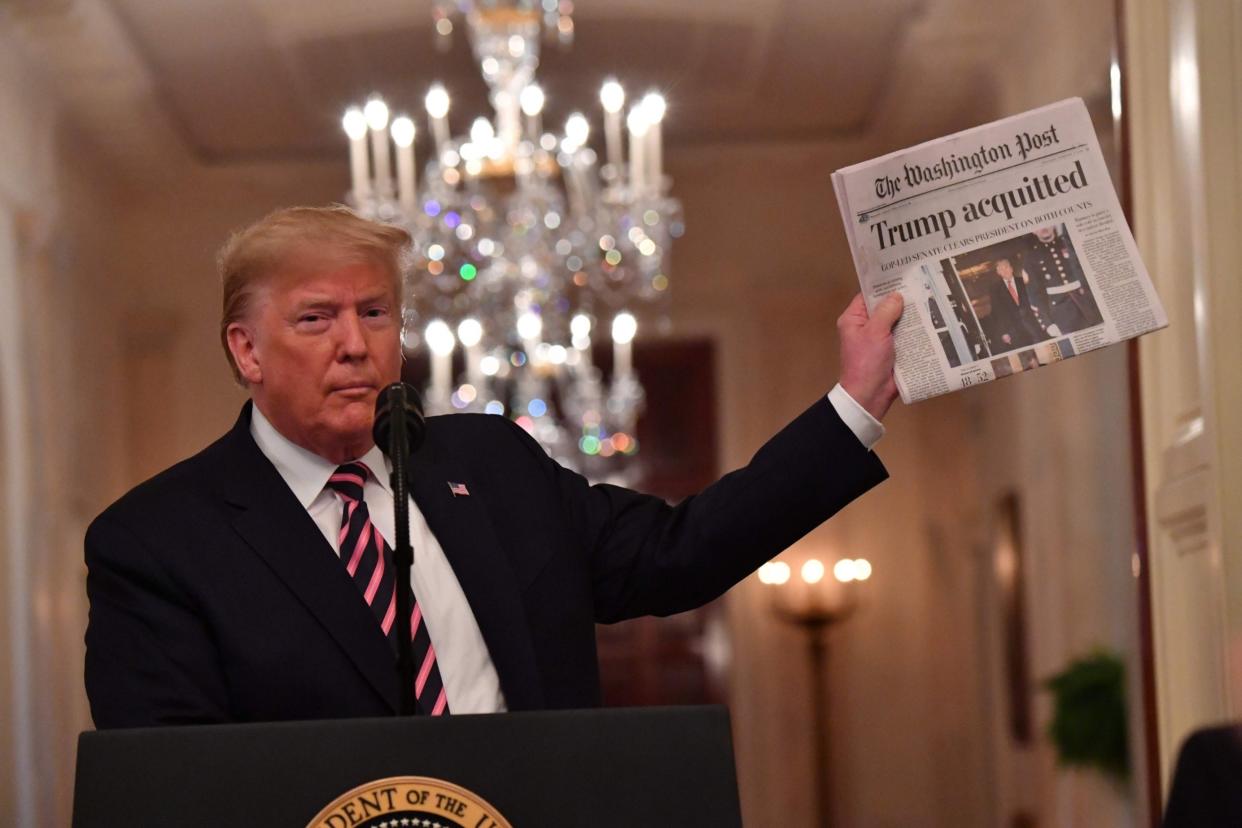 Donald Trump holds up the Washington Post as he speaks to supporters at the White House, following his impeachment acquittal by allies in the Senate: AFP via Getty Images