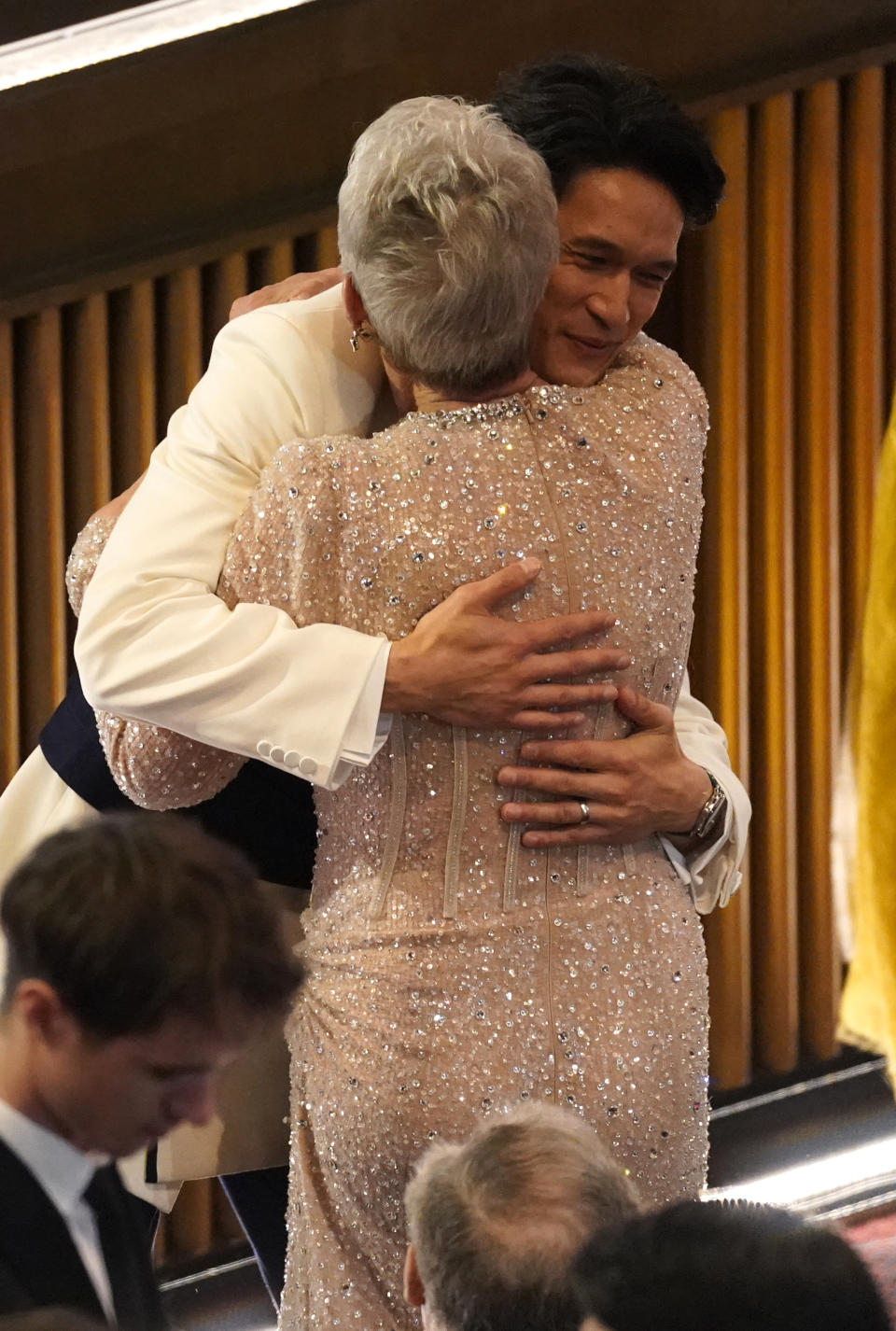 Harry Shum Jr., left, hugs Jamie Lee Curtis in the audience at the Oscars on Sunday, March 12, 2023, at the Dolby Theatre in Los Angeles. (AP Photo/Chris Pizzello)