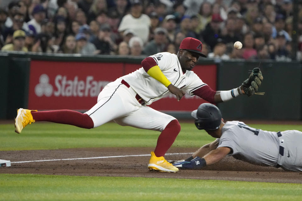 New York Yankees' Anthony Volpe dives into third base safely under the misplayed catch by Arizona Diamondbacks shortstop Geraldo Perdomo in the third inning during a baseball game, Monday, April 1, 2024, in Phoenix. (AP Photo/Rick Scuteri)