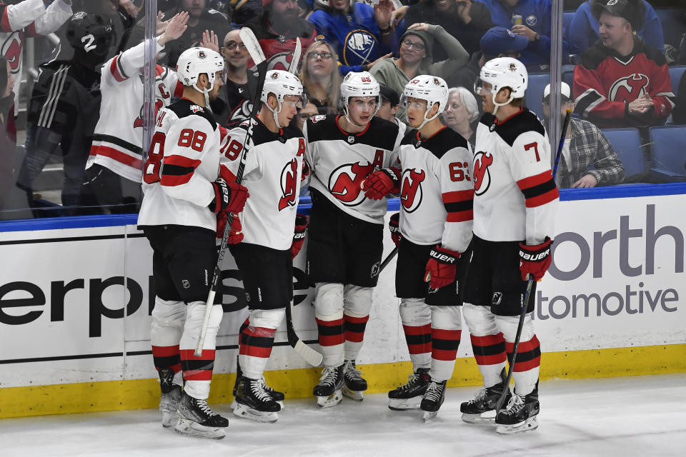 New Jersey Devils center Jack Hughes, center, celebrates with defenseman Kevin Bahl (88), left wing Ondrej Palat (18), left wing Jesper Bratt (63) and defenseman Dougie Hamilton (7) after scoring against the Buffalo Sabres during the third period of an NHL hockey game in Buffalo, N.Y., Friday, March 24, 2023. (AP Photo/Adrian Kraus)