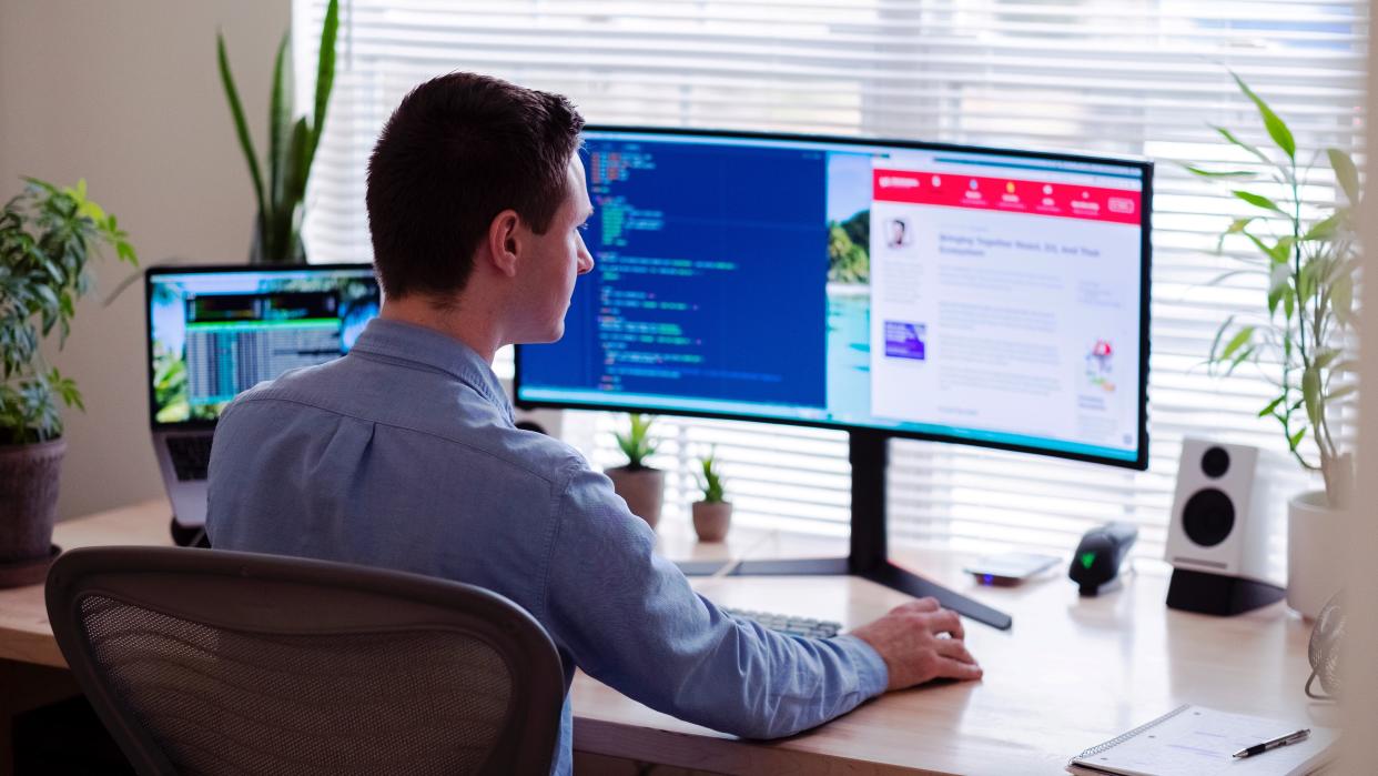  Man working on a laptop with a monitor 