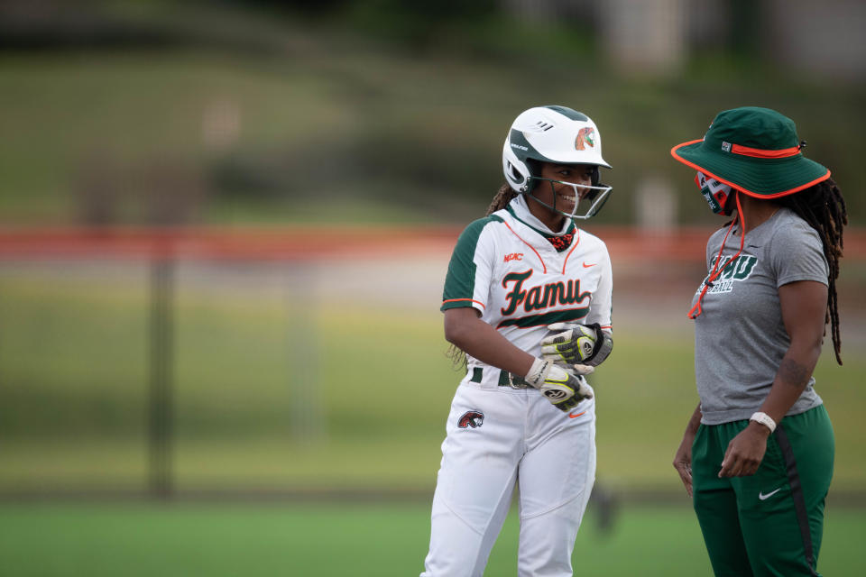 Florida A&M University outfielder Melkayla Irvis (4)  talks with a coach at first base during a doubleheader between FAMU and the University of North Dakota Tuesday, March 9, 2021.