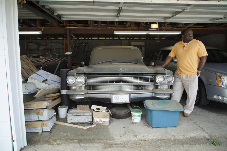 Shawn Troy stands beside the first hearse ever owned by his late father behind the family's funeral home in Mullins, S.C., on Saturday, May 22, 2021. William Penn Troy Sr. died of COVID-19 in August 2020, one of many Black morticians to succumb during the pandemic. (AP Photo/Allen G. Breed)