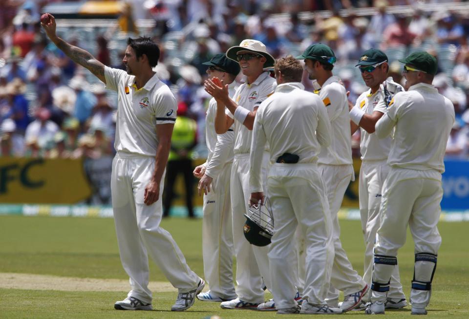 Australia's Mitchell Johnson (L) shows the ball to the crowd as he celebrates taking five wickets in the inning during the third day of the second Ashes test cricket match against England at the Adelaide Oval December 7, 2013.