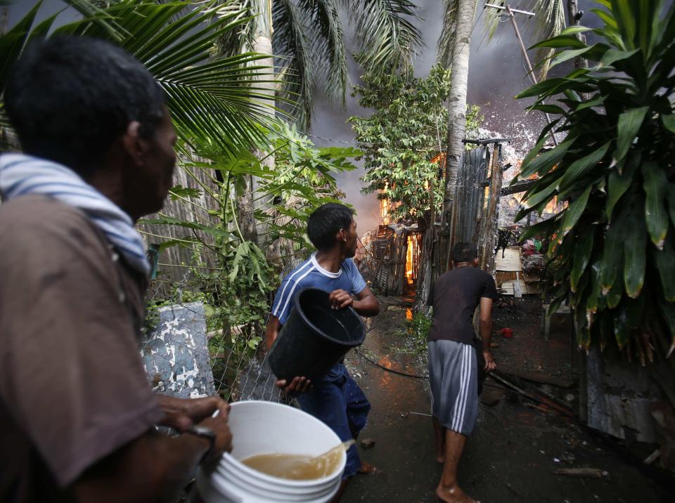 Residents attempt to put out the fire from their burning houses after a firefight between security forces and Muslim rebels from the Moro National Liberation Front (MNLF) in Zamboanga city, in southern Philippines, September 12, 2013. Fighting between security forces and the rogue Muslim rebels seeking to declare an independent state escalated in Zamboanga city on Thursday and spread to a second island, officials said. U.S.-trained commandos exchanged gunfire with a breakaway faction of the MNLF holding dozens of hostages in Zamboanga City, on the southernmost island of Mindanao, army spokesman Domingo Tutaan said. REUTERS/Erik De Castro (PHILIPPINES - Tags: CIVIL UNREST CONFLICT POLITICS)