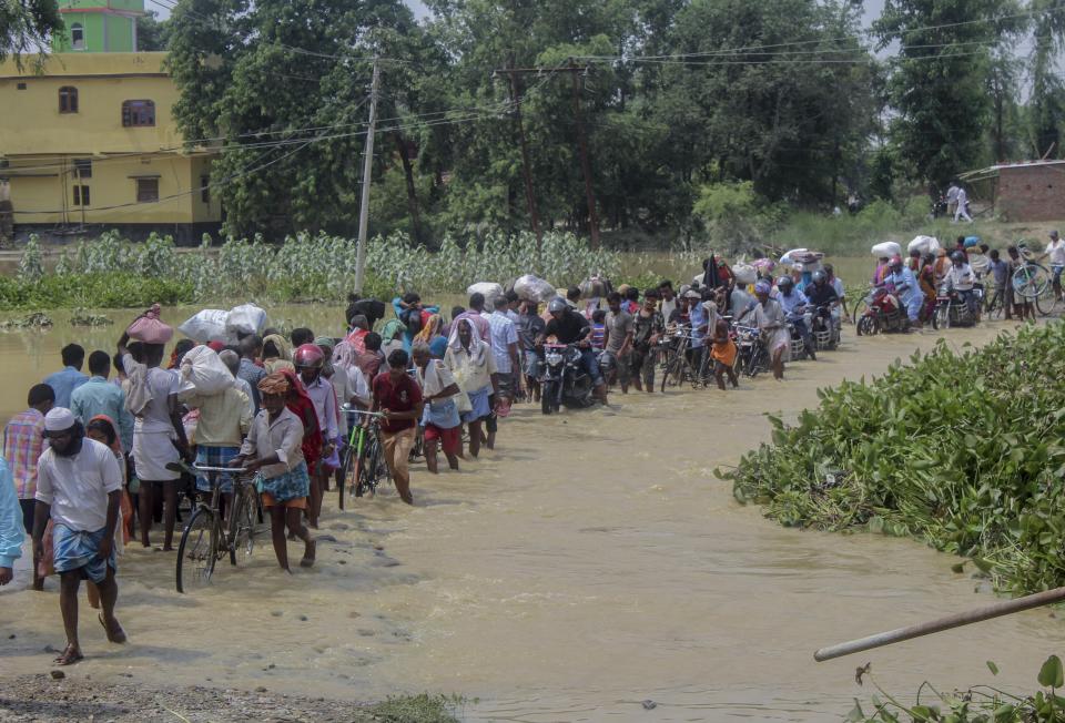 Nepalese people walk through flood waters in Gaur, Rautahat district, Nepal, Monday, July 15, 2019. After causing flooding and landslides in Nepal, three rivers are overflowing in northeastern India and submerging parts of the region, affecting the lives of more than 2 million, officials said Monday. (AP Photo/Manish Paudel)