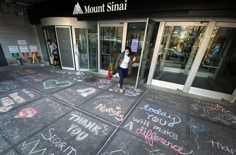 Woman exits Mount Sinai Hospital past messages of thanks to healthcare workers written on sidewalk in New York